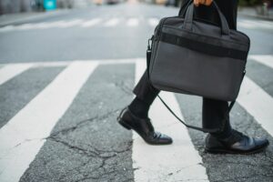 Man walking in black shoes carrying a bag.