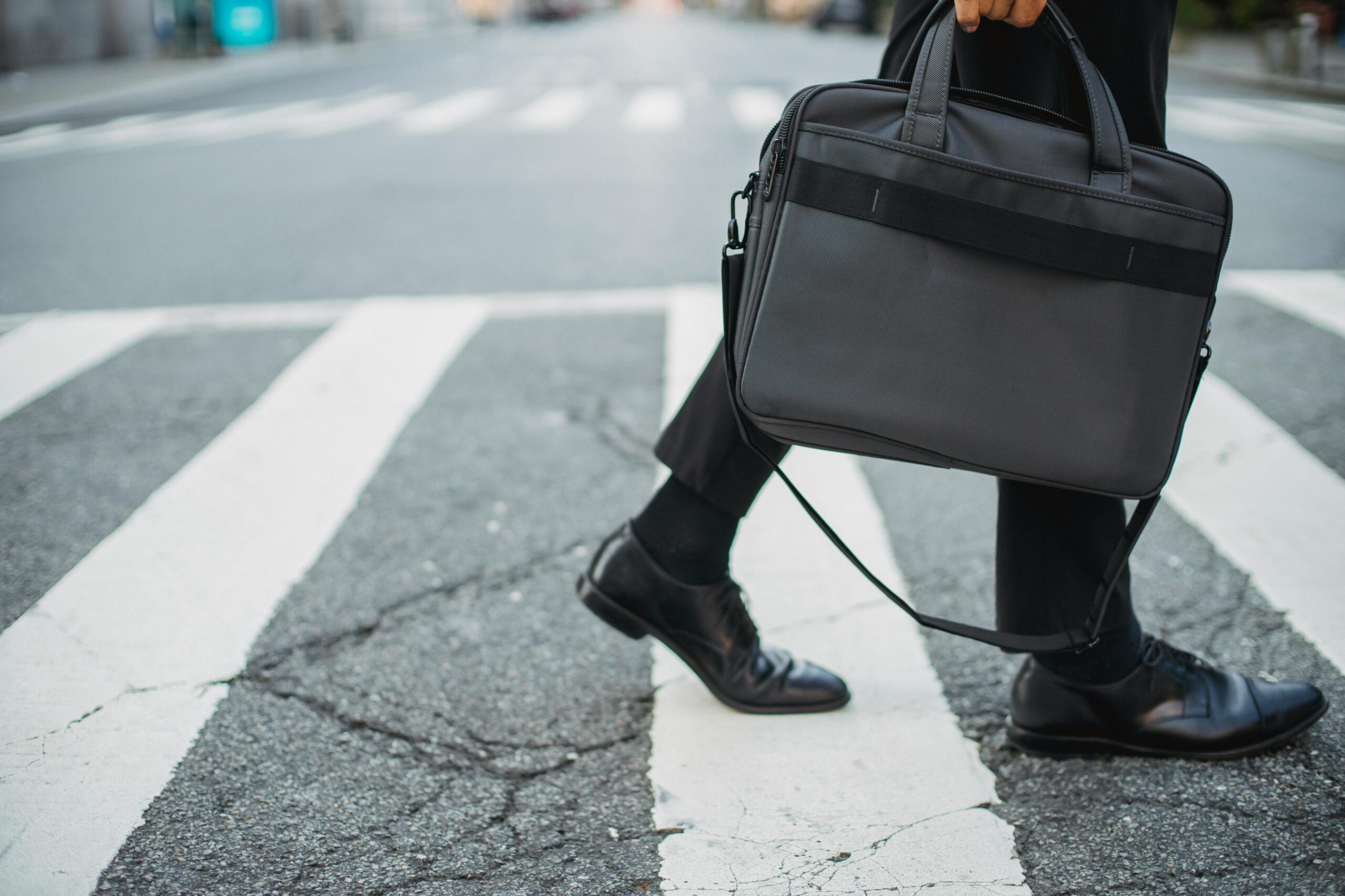 Man walking in black shoes carrying a bag.