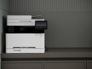 Modern office photocopier and printer on a desk with paper tray.